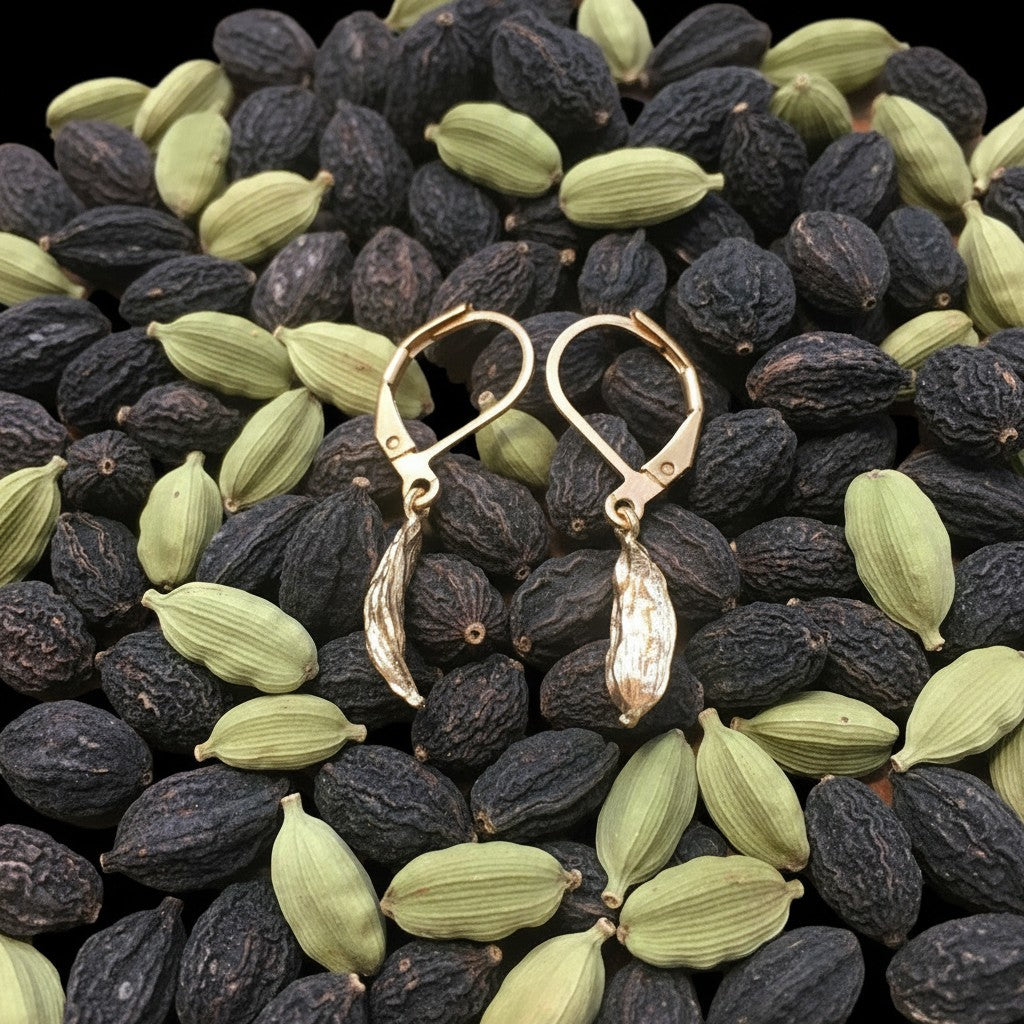 Orecchini MandalaT a forma di baccello di cardamomo in metallo dorato su letto di spezie verdi e nere