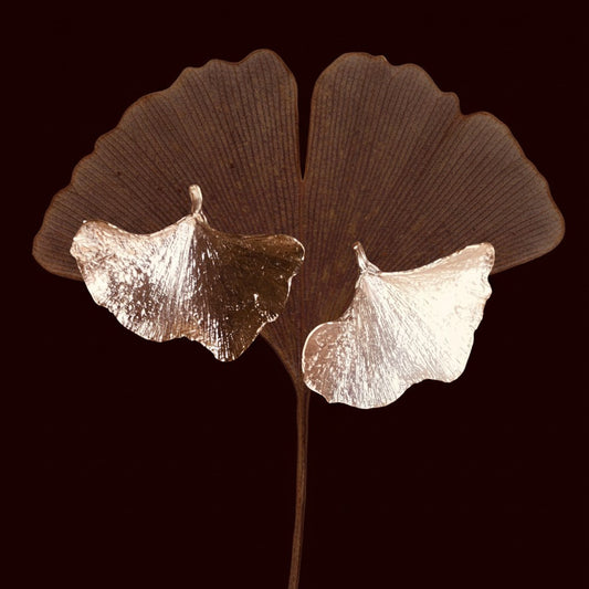 Orecchini MandalaT a forma di foglia di gingko in metallo dorato lucido con texture naturale su sfondo scuro