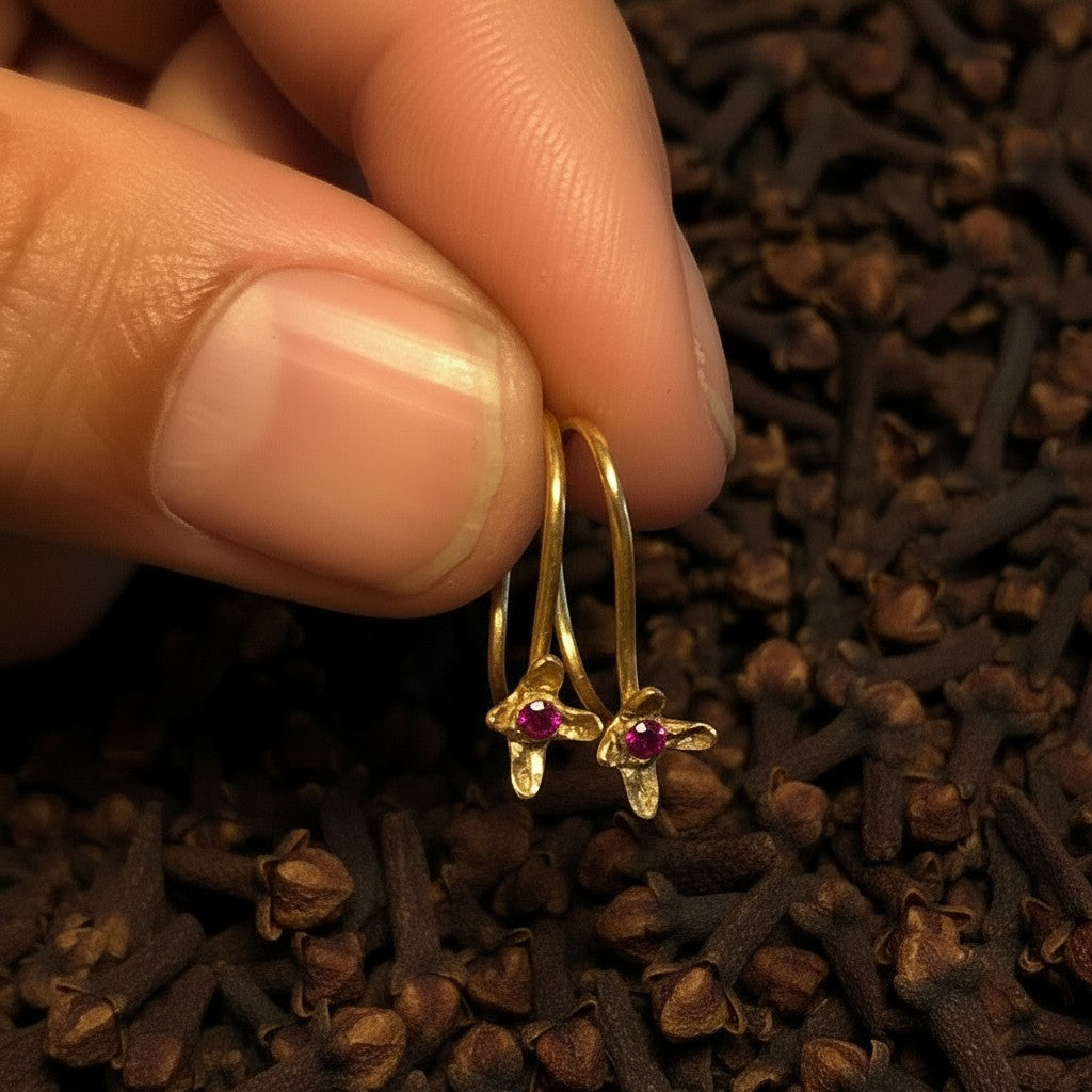 Orecchini ad amo MandalaT Chiodo di garofano in oro con pietra preziosa rossa, tenuti tra le dita