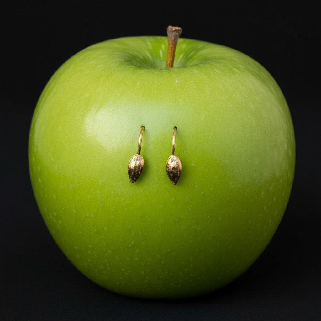 Orecchini MandalaT a forma di seme di mela in oro su mela verde brillante con sfondo nero