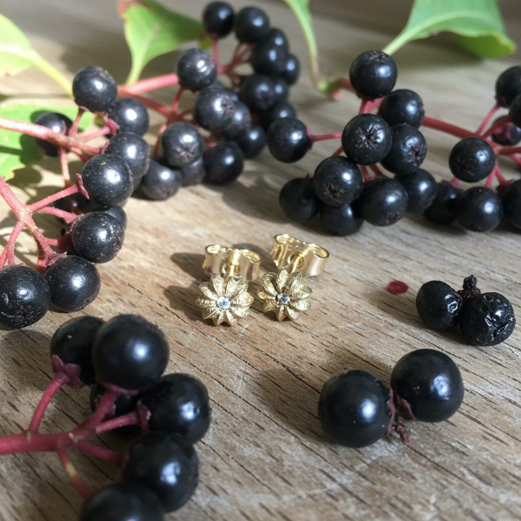 Orecchini a lobo MandalaT Phytolacca in oro a forma di piccolo fiore con dettaglio centrale luminoso su base in legno